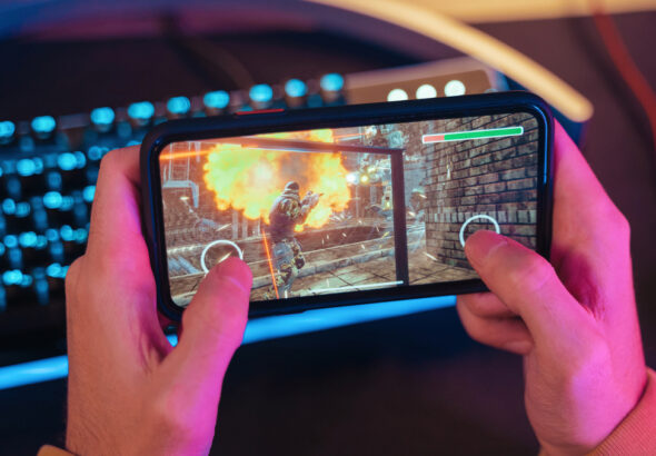 Hands of gamer playing mobile video games on his smartphone